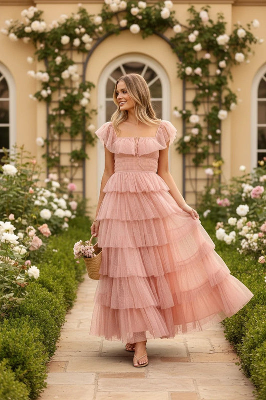 Robe longue Valerelle rose poudré à volants en tulle, portée par une femme dans un jardin fleuri romantique – robe d'invitée de mariage d'occasion