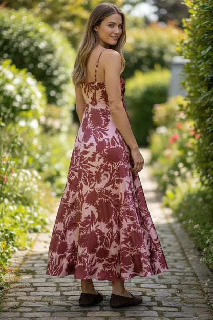 Robe de demoiselle d'honneur Valerelle longue bordeaux à motif floral fluide portée par une femme dans un jardin