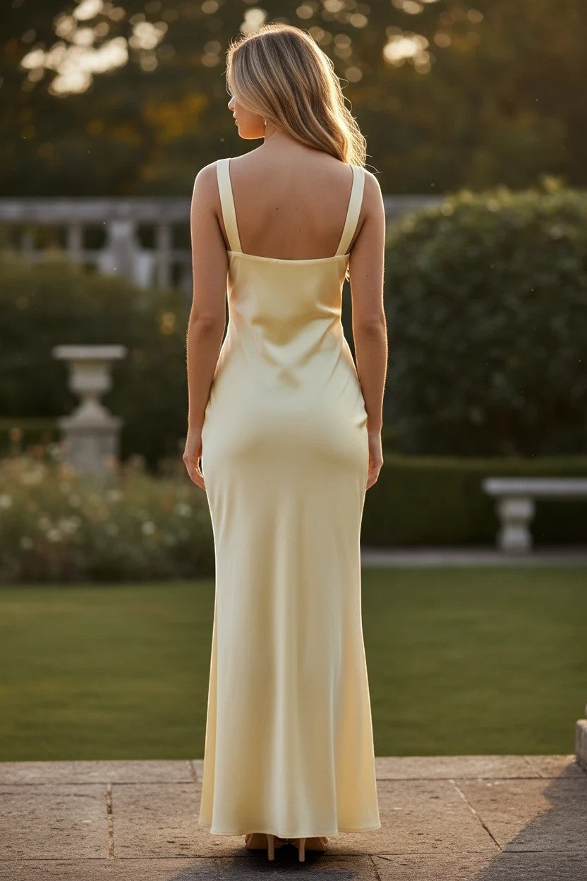 Robe de demoiselle d'honneur Valerelle longue et fluide couleur citron avec encolure arrondie vue de dos dans un jardin