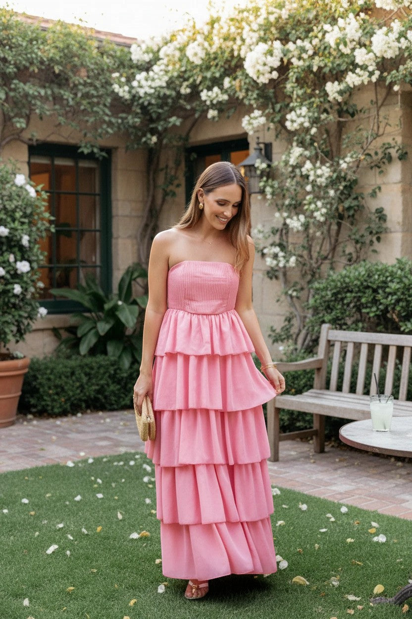 Robe longue Valerelle corail à bustier et volants portée par une femme dans un jardin lors d'un mariage estival