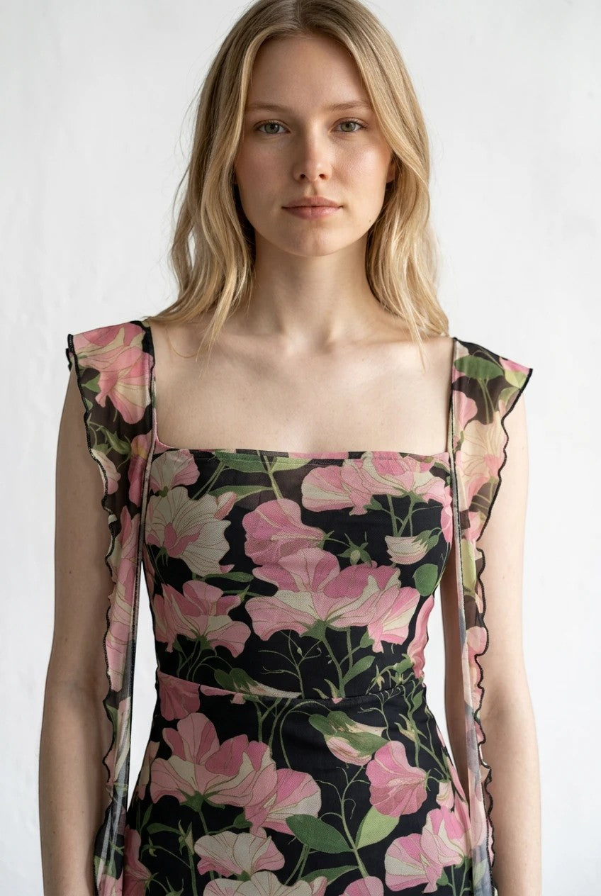 Robe longue Valerelle noire à imprimé floral rose, encolure carrée et bretelles à volants portées par une mannequin