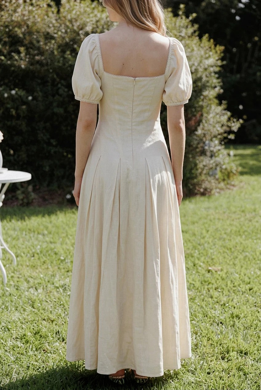 Robe longue Valerelle jaune beurre à manches bouffantes et encolure carrée portée dans un jardin ensoleillé