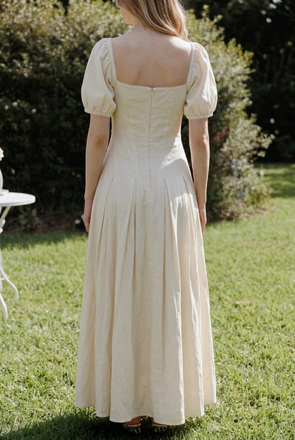 Robe longue Valerelle jaune beurre à manches bouffantes et encolure carrée portée dans un jardin ensoleillé