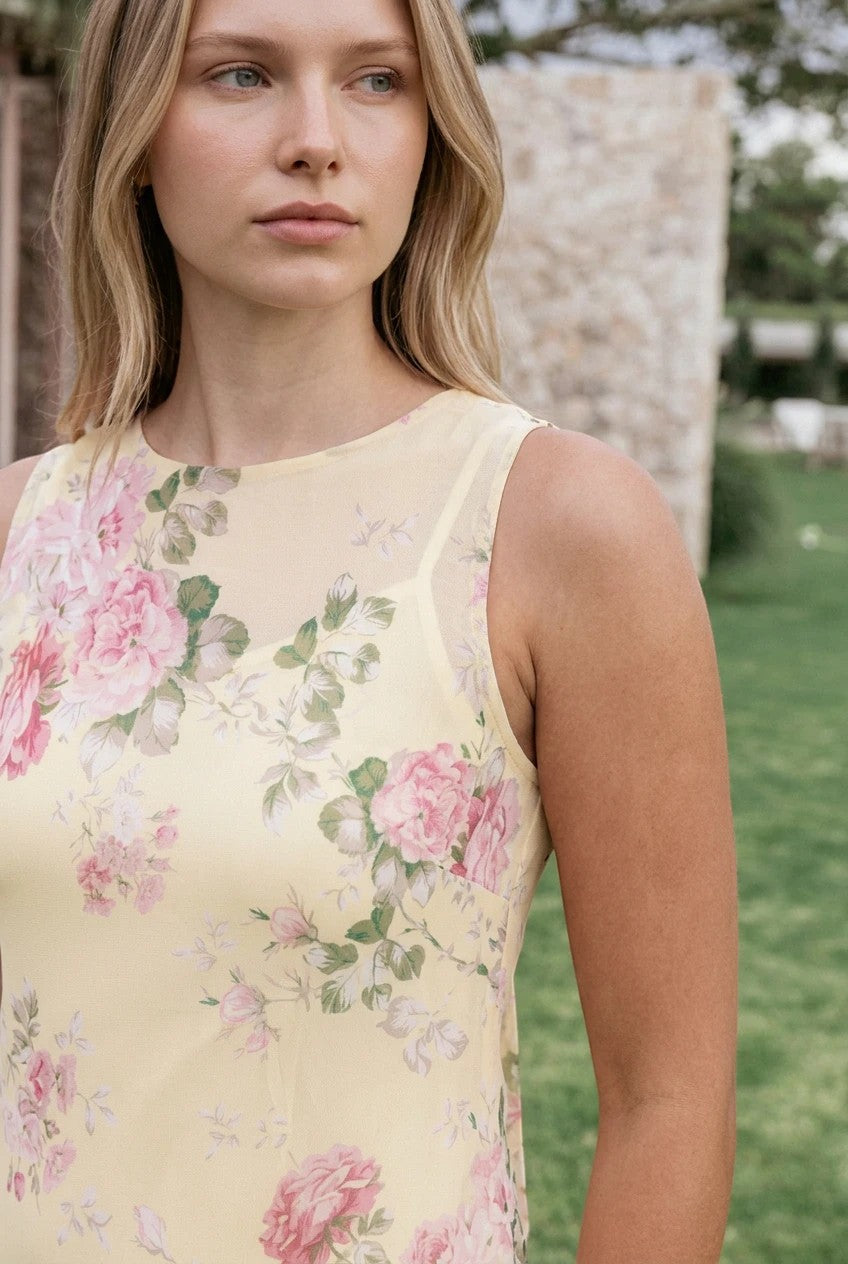 Robe longue Valerelle jaune à imprimé floral portée par une femme blonde dans un jardin