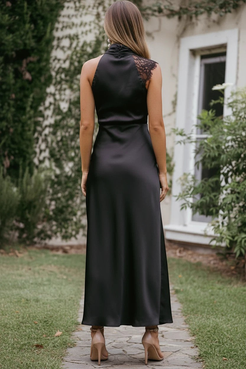 Robe longue Valerelle noire en satin et dentelle avec col licou et dos nu, portée par une femme dans un jardin.
