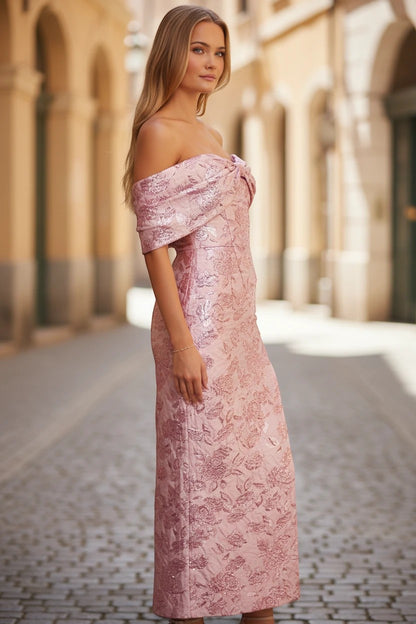 Robe longue Valerelle rose à motif floral brillant avec encolure bardot portée par une femme dans une rue pavée