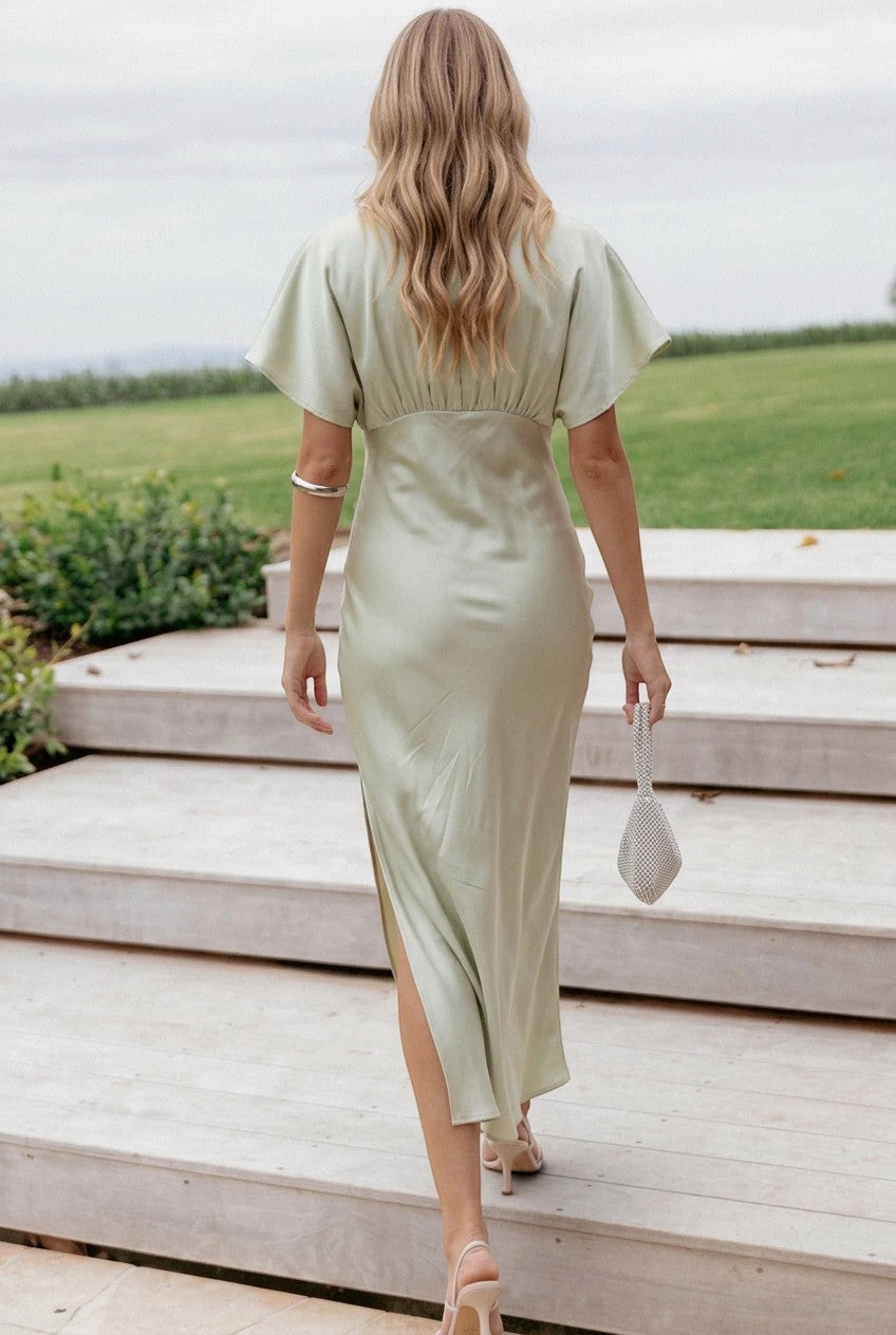 Robe longue Valerelle vert sauge fluide avec manches courtes et fente latérale portée par une femme de dos