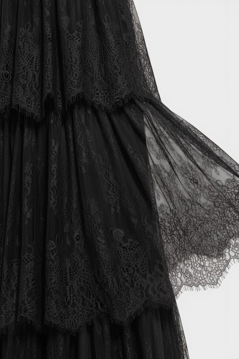 Gros plan sur la dentelle noire raffinée d'une robe de soirée longue Valerelle avec des détails de volants délicats.