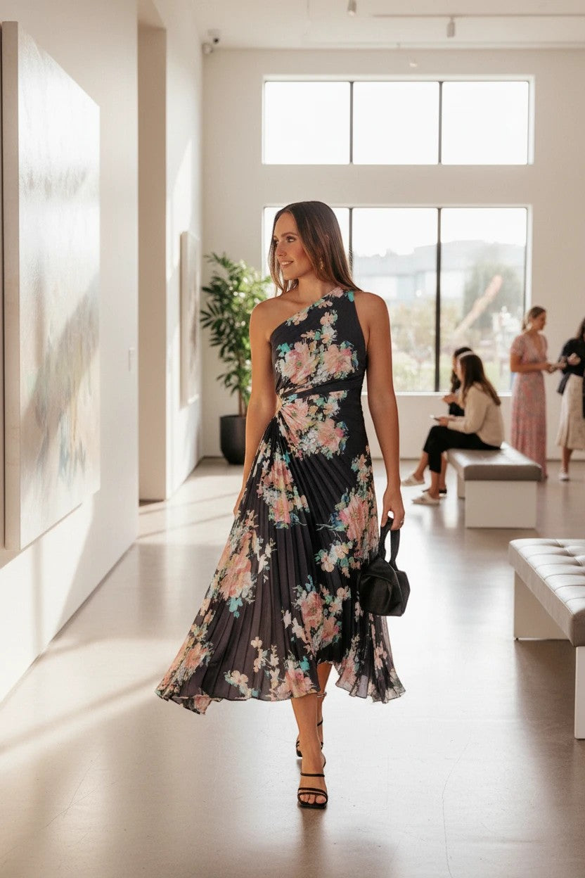 Robe de soirée longue Valerelle asymétrique une épaule à imprimé floral portée par une femme dans une galerie d'art