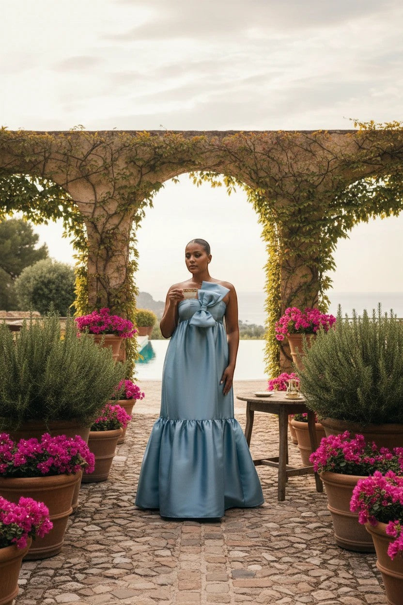 Robe de soirée longue Valerelle bleu profond avec nœud à la taille, portée par une femme dans un jardin méditerranéen.