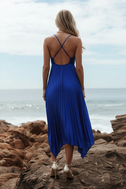 Robe de soirée longue Valerelle bleu roi plissée avec dos nu croisé portée par une femme sur des rochers en bord de mer