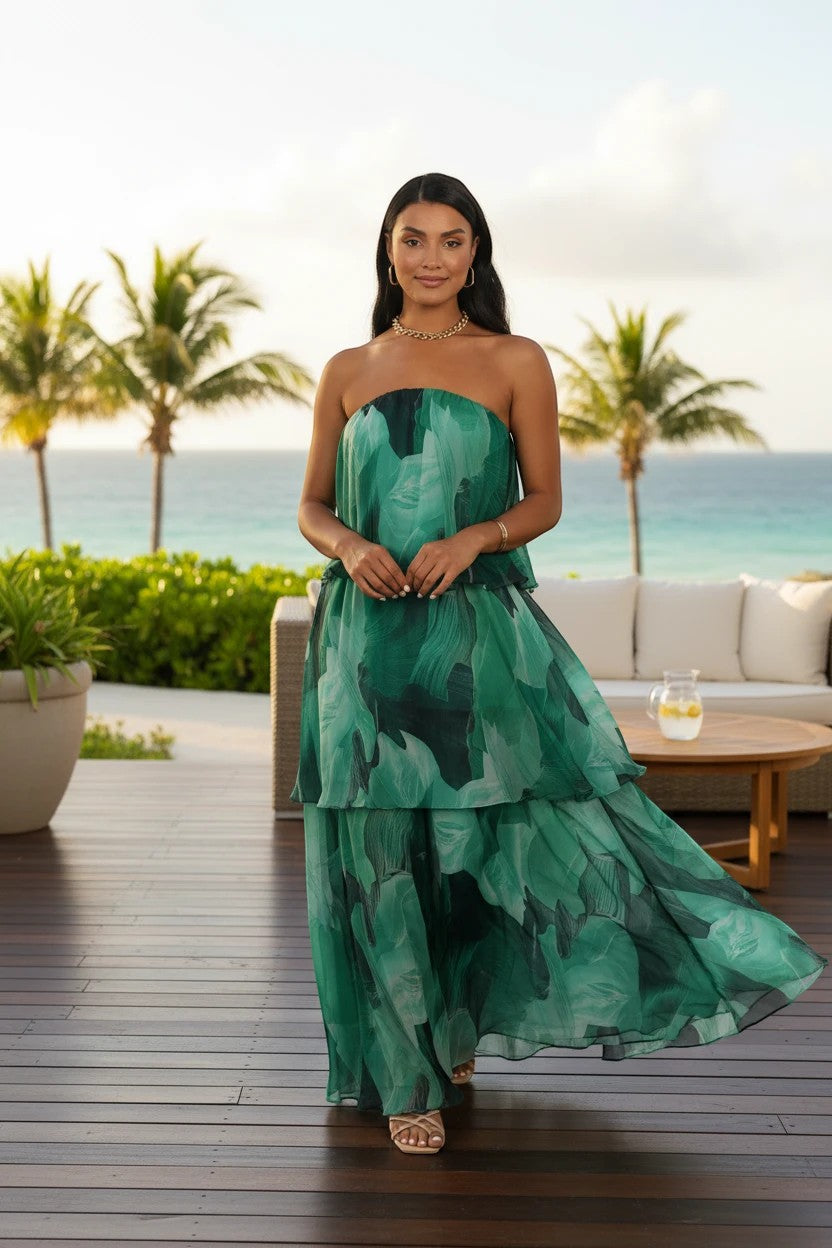 Robe de soirée longue Valerelle bustier à imprimé floral vert portée par une femme sur une terrasse en bord de mer