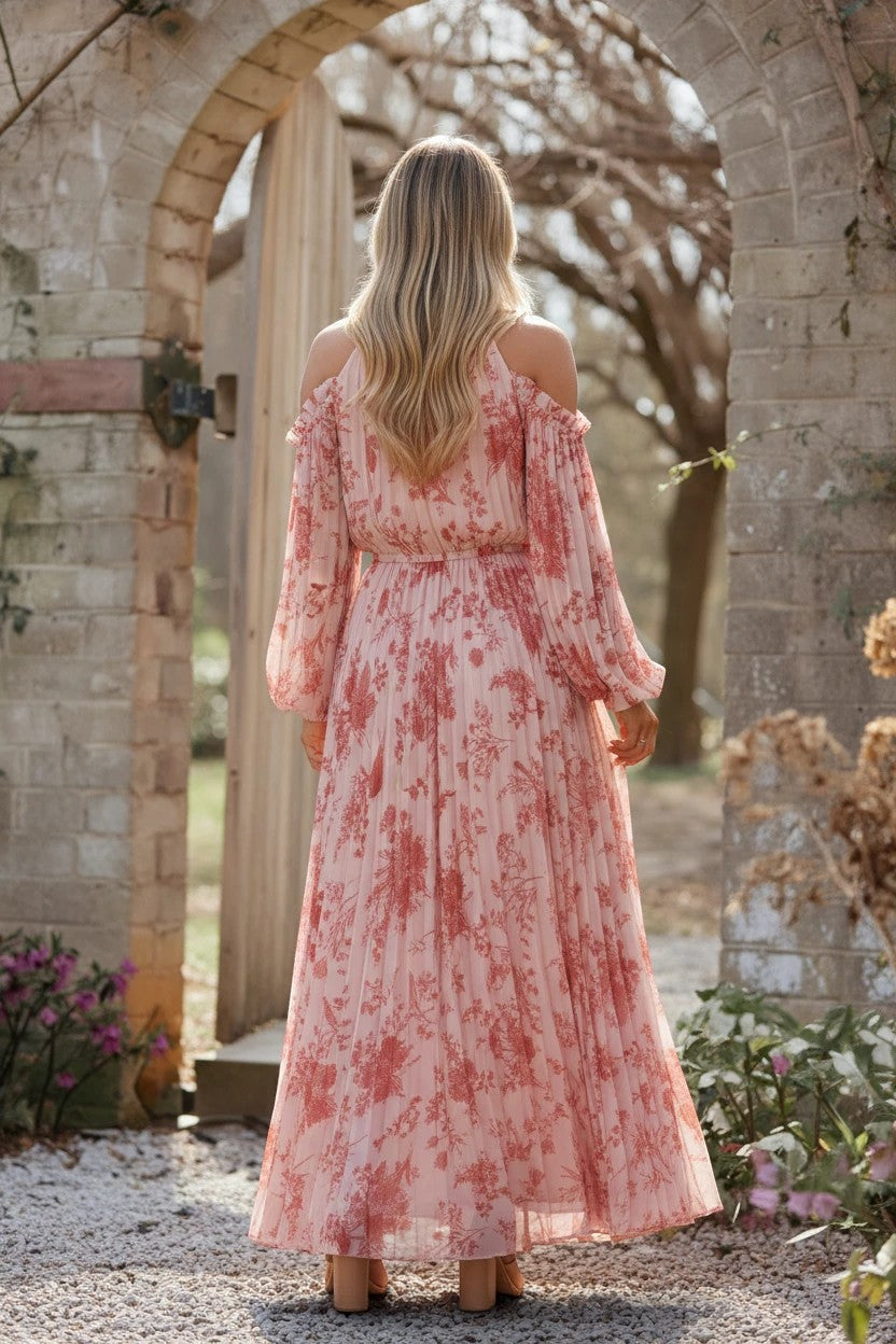 Robe de soirée longue Valerelle plissée à imprimé floral rose, épaules dénudées et manches longues fluides.